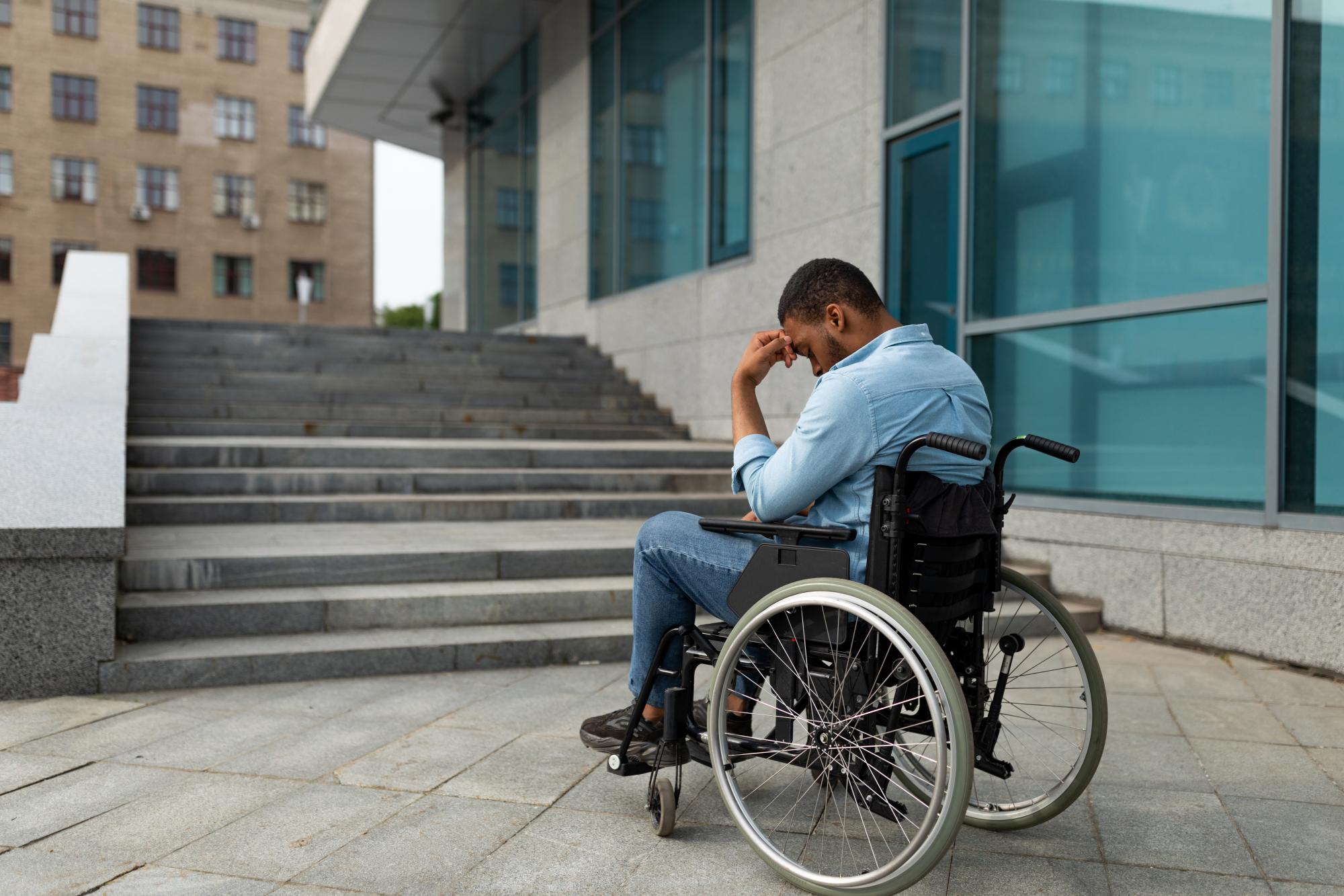 Man in wheelchair sitting looking at steps Man in wheelchair sitting looking at steps