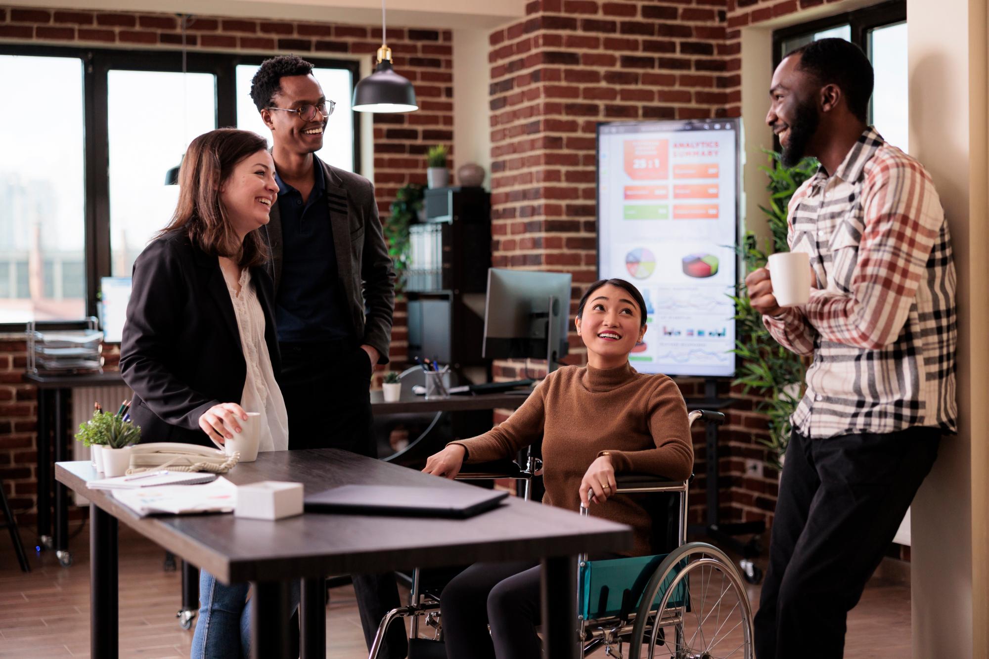Four people having a conversation, one person sitting on a wheelchair Four people having a conversation, one person sitting on a wheelchair