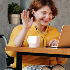 Women in wheelchair sitting at table using computer Women in wheelchair sitting at table using computer