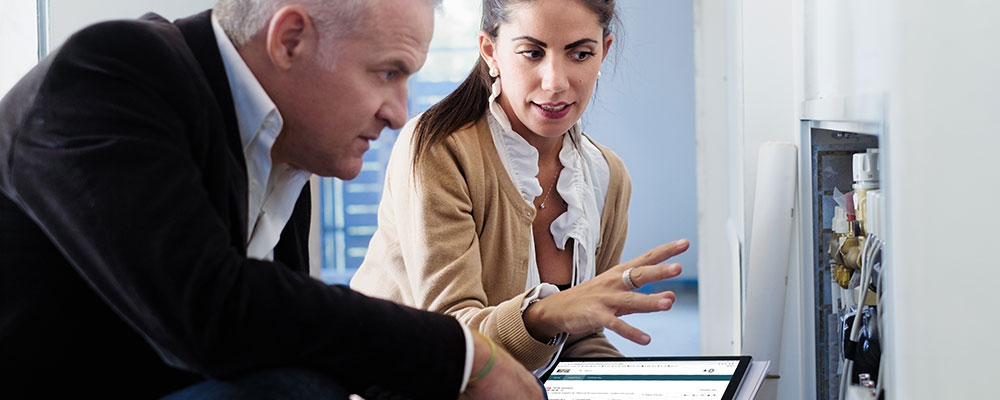 An inspector holds a tablet and discusses electrical features with a property representative.