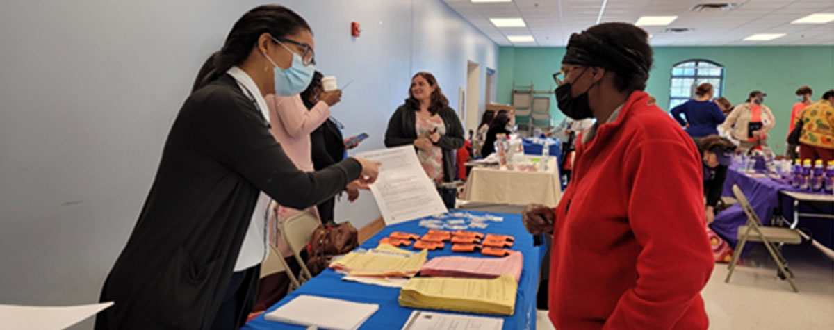 [MRHA No. VIII employee, Liz Nunez, talks with health fair attendee.]. HUD Photo